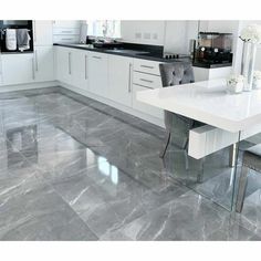 a modern kitchen with marble floors and white cabinetry, stainless steel table and chairs