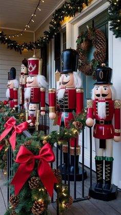 nutcrackers are lined up on the front porch for christmas time, with pine cones and garland around them