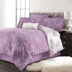 a bed with purple comforters and pillows