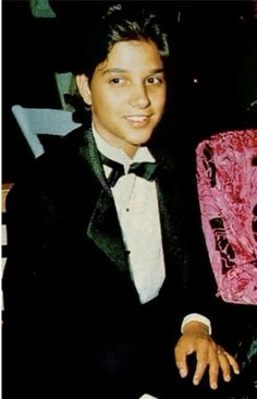 a young man in a tuxedo and bow tie sitting next to an older gentleman