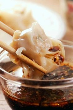 two chopsticks are sticking out of some food in a glass bowl on a table