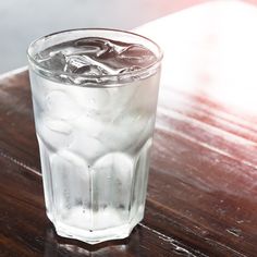 a glass filled with ice sitting on top of a wooden table