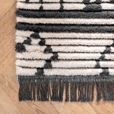 an area rug with black and white designs on the top, along with wood flooring