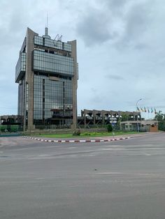 an empty parking lot in front of a large building with many windows on the side