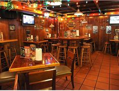 the inside of a restaurant with wooden tables and chairs, televisions on the wall