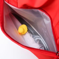 a small yellow object is in the pocket of a red bag on a white surface