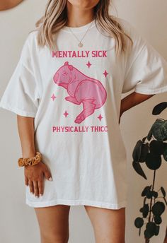 Embrace your unique style and sense of humor with our "Mentally sick physically thick" Capybara shirt. This funny t-shirt serves as a witty reminder that mental health is an essential part of who you are, and it's okay to celebrate your individuality. Wear it with pride, knowing you're part of a community that promotes mental health awareness and self-acceptance. Embrace your thick-skinned spirit while nurturing your mental well-being. This shirt makes the perfect gift for your weirdcore friends Cheap Funny Print Graphic Tee, Funny Streetwear T-shirt, Cheap Artistic Tops With Funny Print, "funny T-shirt", Capybara Shirt, Girly Preppy, Denki Kaminari, Funny Graphics, Funny Meme