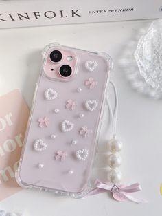 an iphone case with pearls and bows on it next to a pink broochie