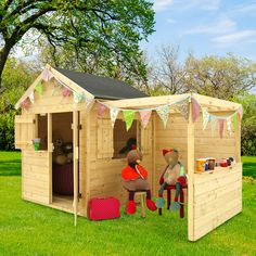 a wooden play house with two teddy bears sitting in the front and one bear standing outside