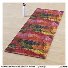 a multicolored rug on the floor next to a white water bottle and pen