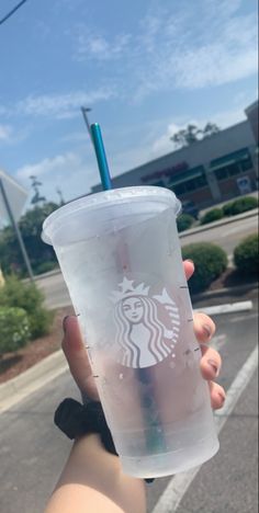 a person holding up a plastic cup with a straw in it