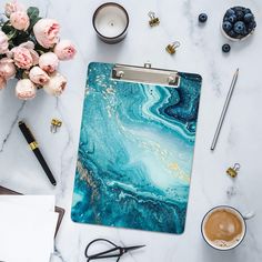 a clipboard with blue marble on it next to some flowers and other office supplies