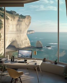 a desk with a computer sitting on top of it next to a large window overlooking the ocean