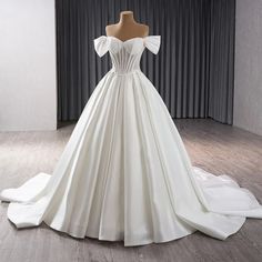 a white wedding dress on display in front of a curtain