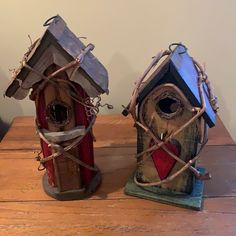 two bird houses with barbed wire around them on a wooden table in front of a white wall