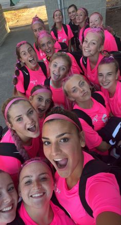 a group of women in pink shirts are posing for a photo with their heads together