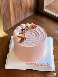 there is a pink cake with fruit on the top and frosting in the middle