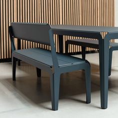 a table and two benches in front of a wall with wood slats on it