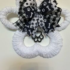 a black and white dog hair bow with paw prints on it, attached to a crocheted headband