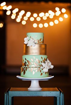 a three tiered cake sitting on top of a blue table with lights in the background