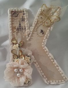 the letter k is decorated with flowers and pearls