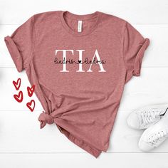 If you're looking for a personalized or custom auntie shirt for your favorite aunt then this Tia with the names of the nephews/nieces is perfect for you. Note: JUST ADD THE NAMES OF THE KIDS ON THE SPACE BELOW. You've now found the staple t-shirt of your wardrobe. It's made of a thicker, heavier cotton, but it's still soft and comfy. And the double stitching on the neckline and sleeves add more durability to what is sure to be a favorite! * 100% ring-spun cotton * Sport Grey is 90% ring-spun cot Custom Print Cotton Tops For Personalized Gifts, Custom Print Cotton Tops As Personalized Gift, Custom Print Cotton Top As Personalized Gift, Custom Text Cotton Tops For Personalized Gift, Personalized Relaxed Fit Cotton Tops, Personalized Cotton T-shirt With Custom Text, Custom Text Cotton T-shirt For Personalized Gift, Personalized Casual Tops For Teacher Appreciation, Custom Text Cotton T-shirt As Personalized Gift