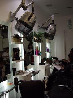 a hair salon with lights hanging from the ceiling and people sitting in chairs around it