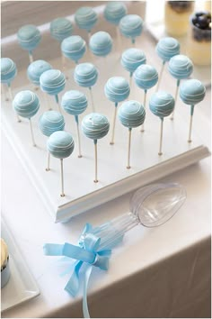 there are many blue cake pops on the table and one has a light blue bow