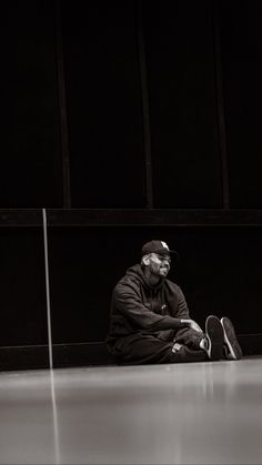 an old man sitting on the ground with his skateboard in front of him and wearing a hat