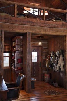 the inside of a log cabin with wood floors and walls, coat racks on the wall