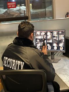 a man sitting in front of a computer monitor holding a cell phone to his ear