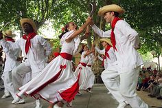 several people dressed in white and red dancing