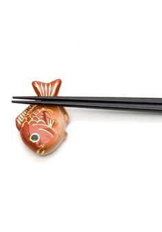 two chopsticks and a fish on a white surface