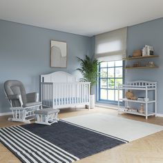 a baby's room with blue walls and white furniture