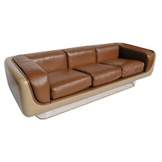 a brown leather couch sitting on top of a white floor