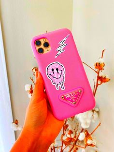 a person holding up a pink phone case with an animal sticker on the back