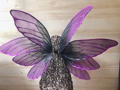 a purple and black butterfly sitting on top of a vase