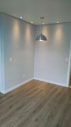 an empty room with hard wood flooring and lighting on the ceiling is pictured in this image