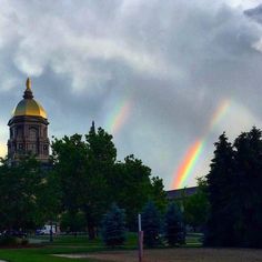 two rainbows are seen in the sky over a building with a dome on top