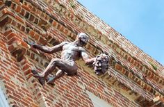 a statue of a man climbing up the side of a brick building