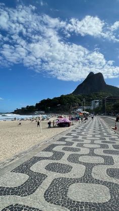 people are walking on the beach with umbrellas