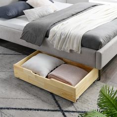 a bed with two pillows in it and a wooden box underneath the bed's headboard