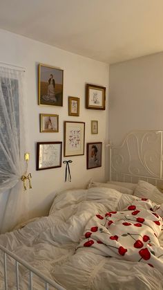 a bed with white sheets and red flowers on it in a room with many framed pictures