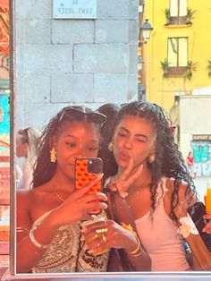 two women are taking a selfie in front of a store window with their cell phone