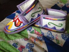 two pairs of shoes are sitting on top of a quilted bed spread with butterflies and flowers