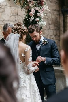 a man in a suit and tie standing next to a woman wearing a wedding dress