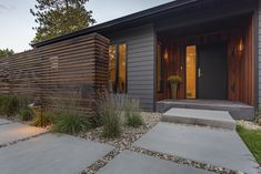 a modern home with wood siding and stone walkway leading up to the front door area