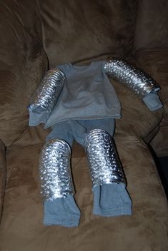 a stuffed animal that is sitting on top of a brown couch with silver leggings