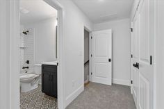 an empty bathroom with white walls and tile flooring is seen through the doorway to another room