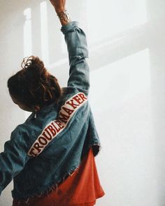 a woman standing in front of a window with her arms up